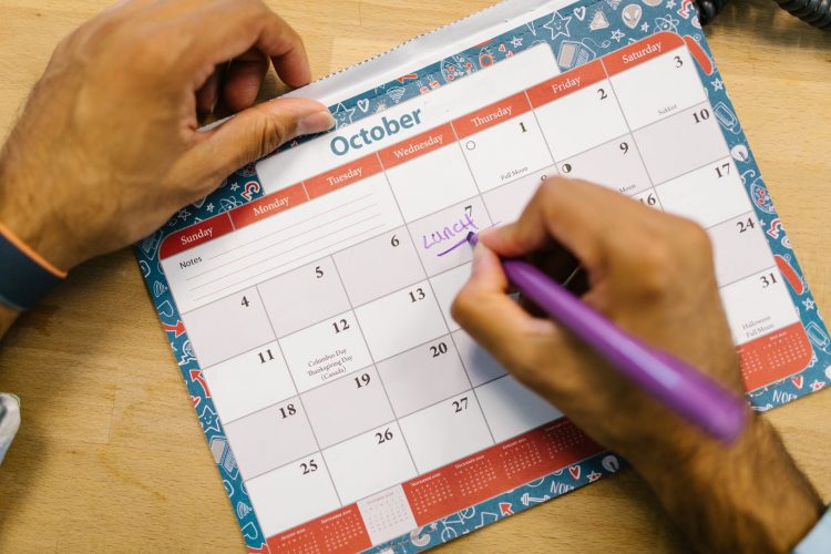 A hand writing dates on an October wall planner