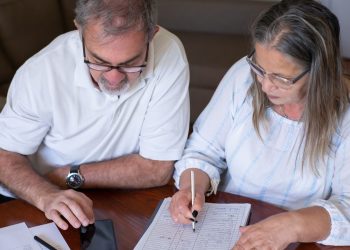 Record tax-free withdrawals risk leaving savers worse off in later retirement: an older couple going through pension and retirement paperwork together at home