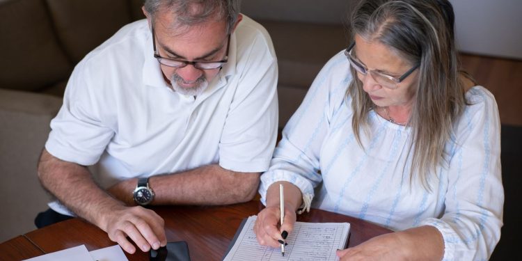 Record tax-free withdrawals risk leaving savers worse off in later retirement: an older couple going through pension and retirement paperwork together at home