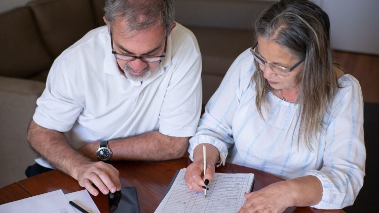 Record tax-free withdrawals risk leaving savers worse off in later retirement: an older couple going through pension and retirement paperwork together at home